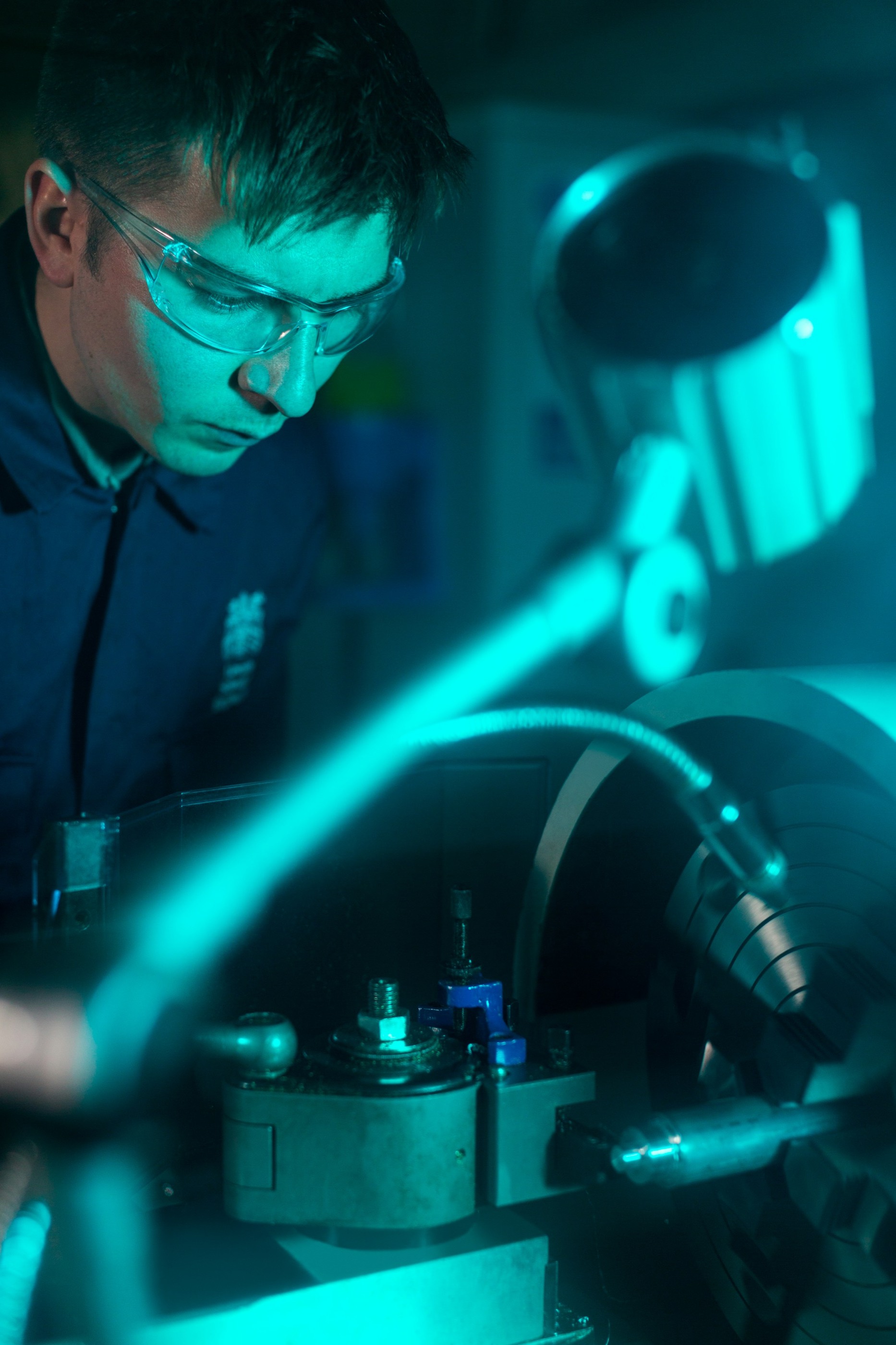 Engineer validating a precision machining prototype under cyan work light